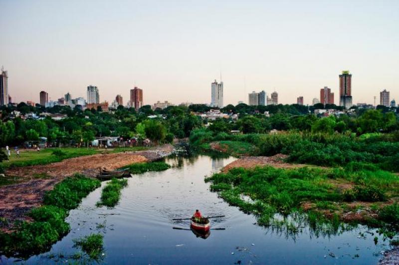 A boat is sailing on a river in Paraguay with city buildings on the horizon